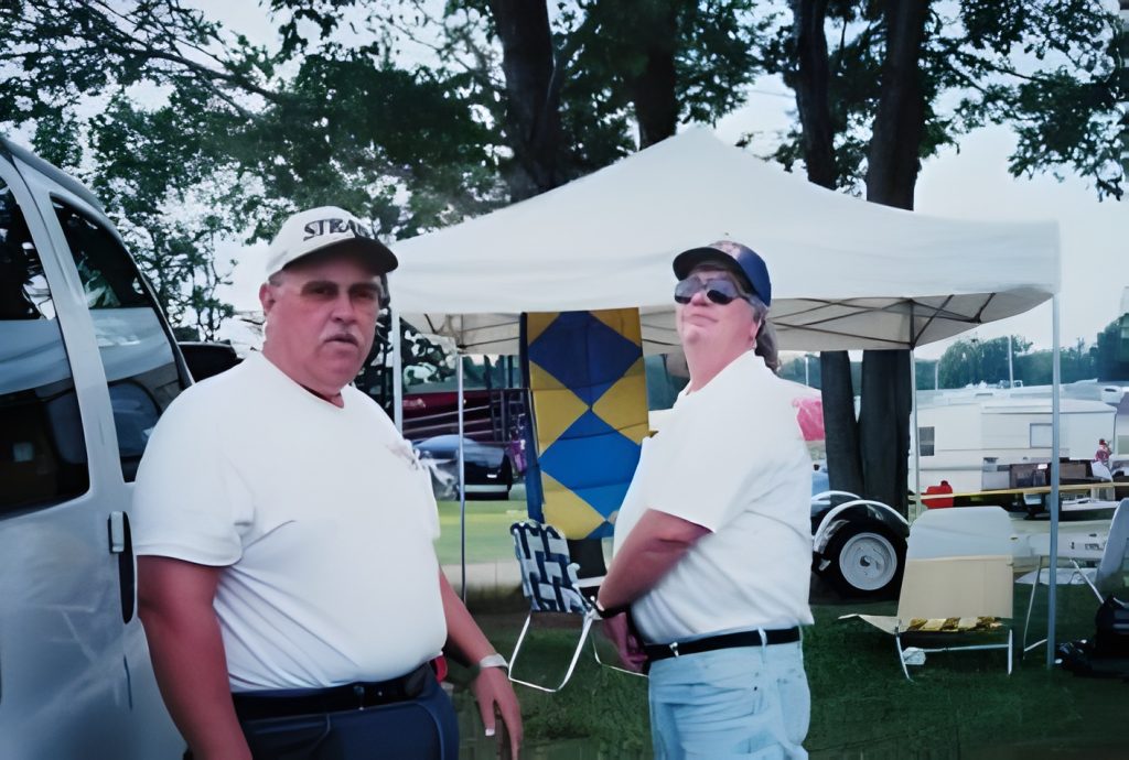 Two men at outdoor event with a tent.