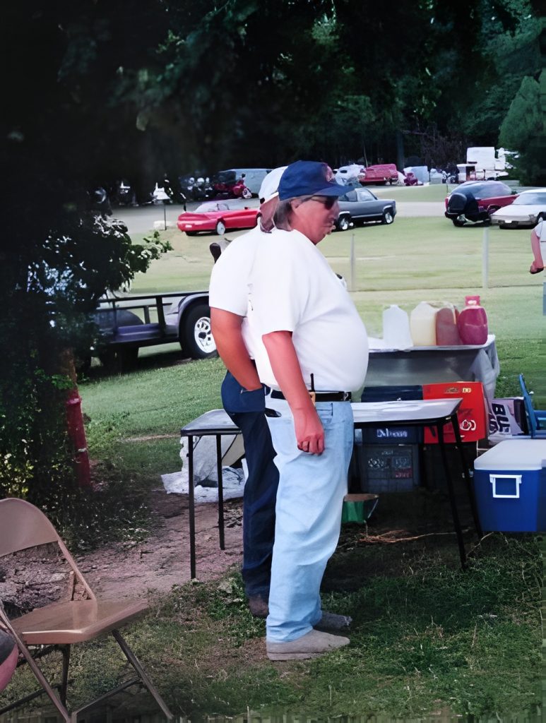 Two people standing near outdoor table and supplies.