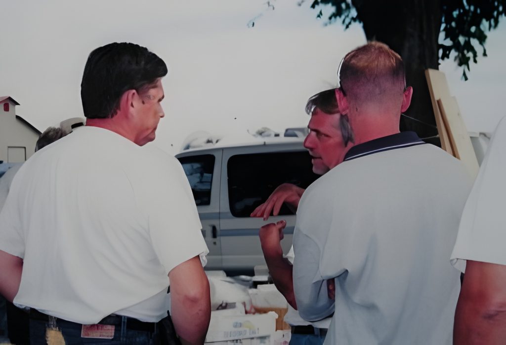 Men discussing outside near a parked van.