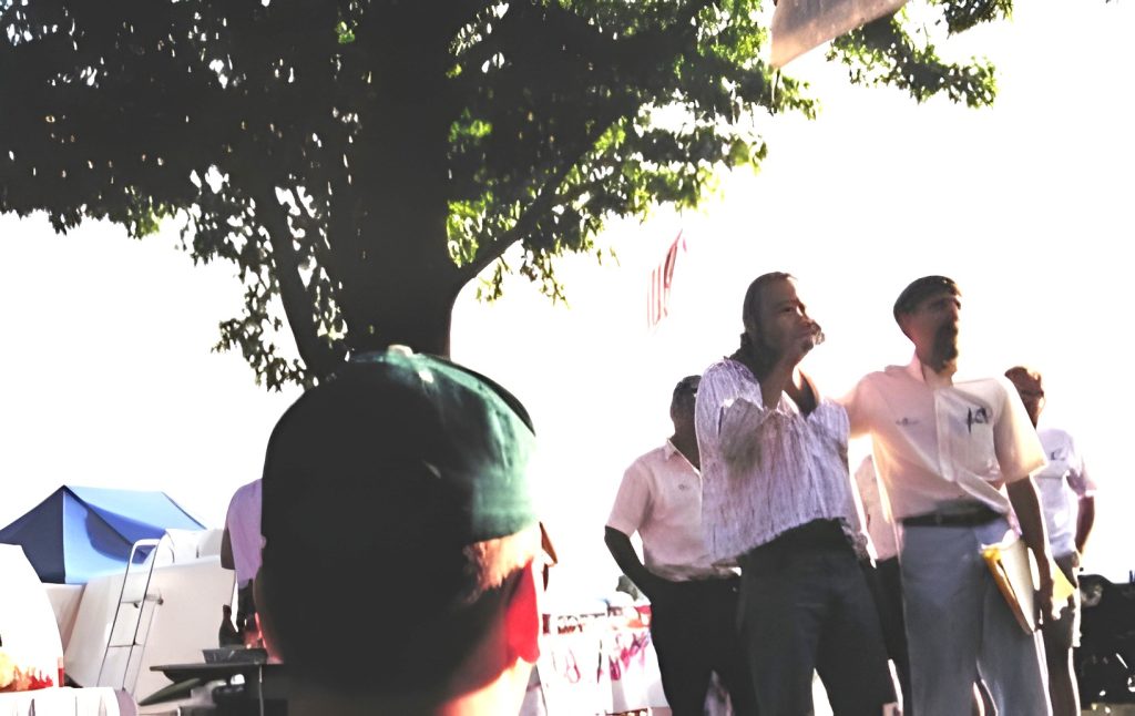 People gathered outdoors at an event under trees.