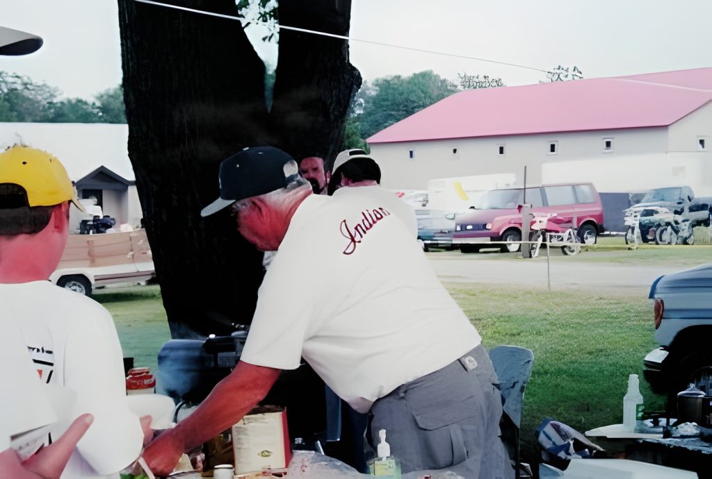Man grilling at outdoor event under tree
