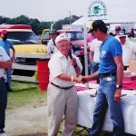 Two men shaking hands at outdoor event.
