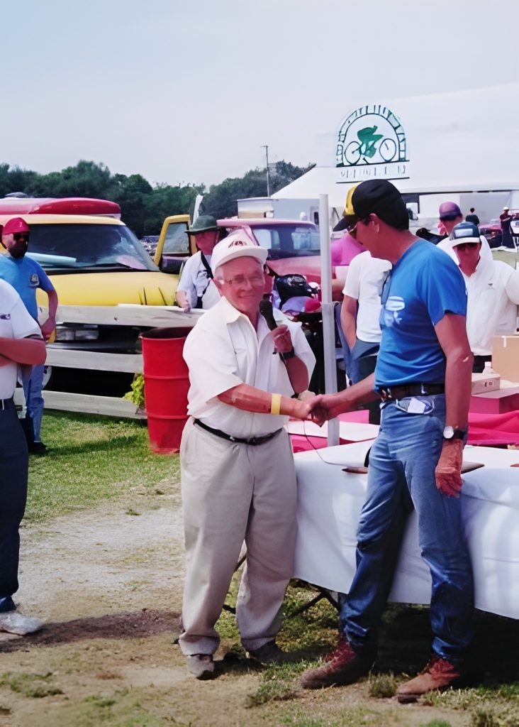 Two men shaking hands at outdoor event.