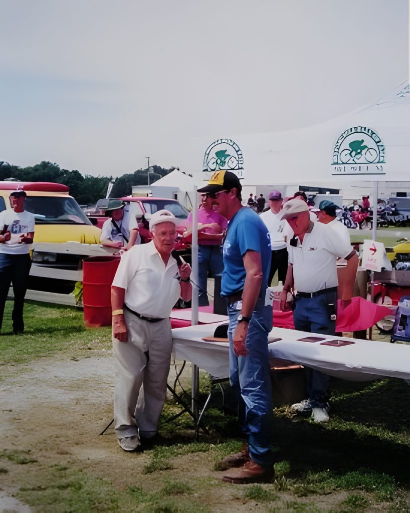 Outdoor event with people and classic cars.