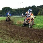 Dirt bikers racing on grassy track.