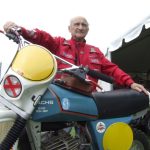 Man with vintage Sachs motorbike at outdoor event.