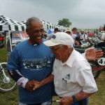 Two men shaking hands at a motorcycle event.