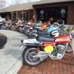 Row of vintage motorcycles on display outdoors.
