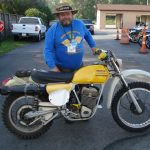 Man with vintage Penton dirt bike outdoors.