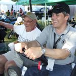 Two men in a golf cart, smiling.