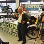 Man speaking at Penton motorcycles event with audience.