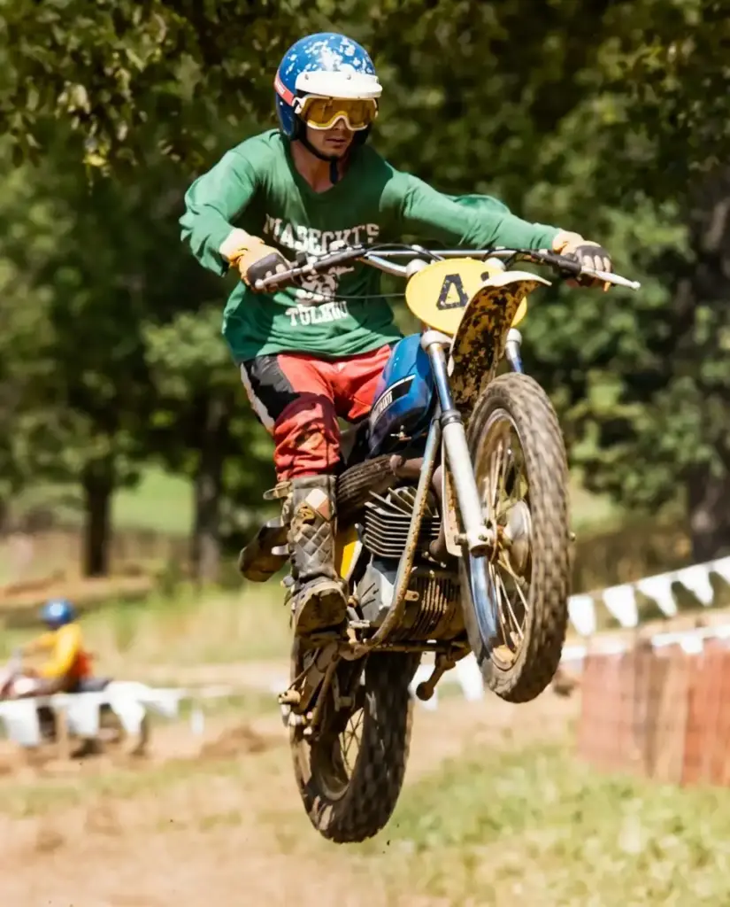 Rider jumps motocross bike on dirt track.