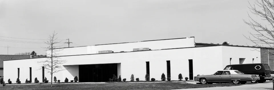 Modern white building with parked vintage cars.