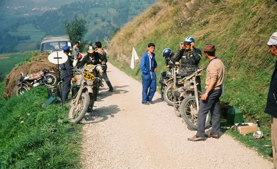Motorcyclists preparing for off-road adventure on rural path.